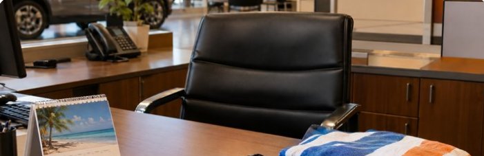 Empty F&I office chair with vacation items on the desk